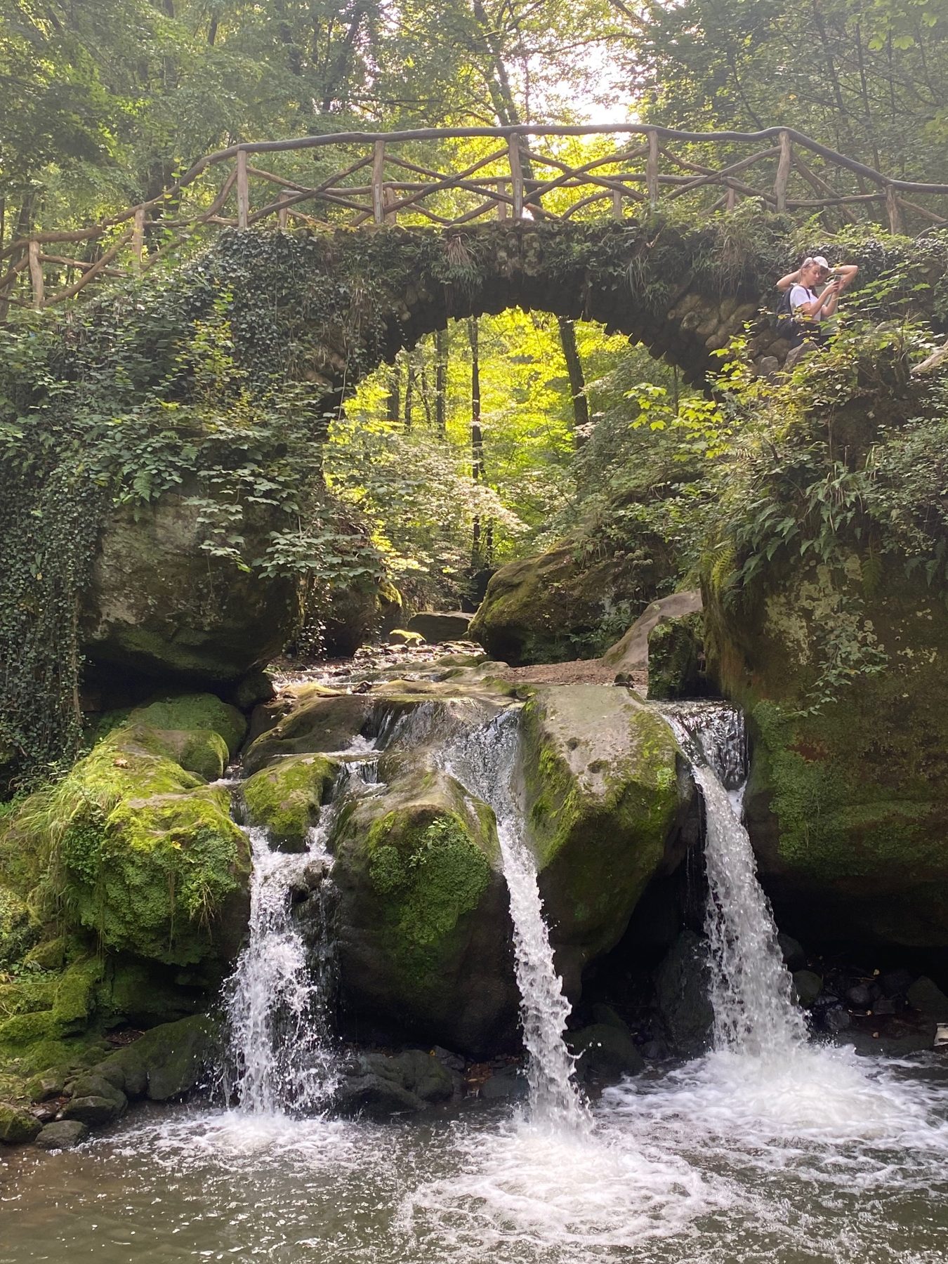 Cascade sous un vieux pont de pierre et de bois, au Mullerthal
