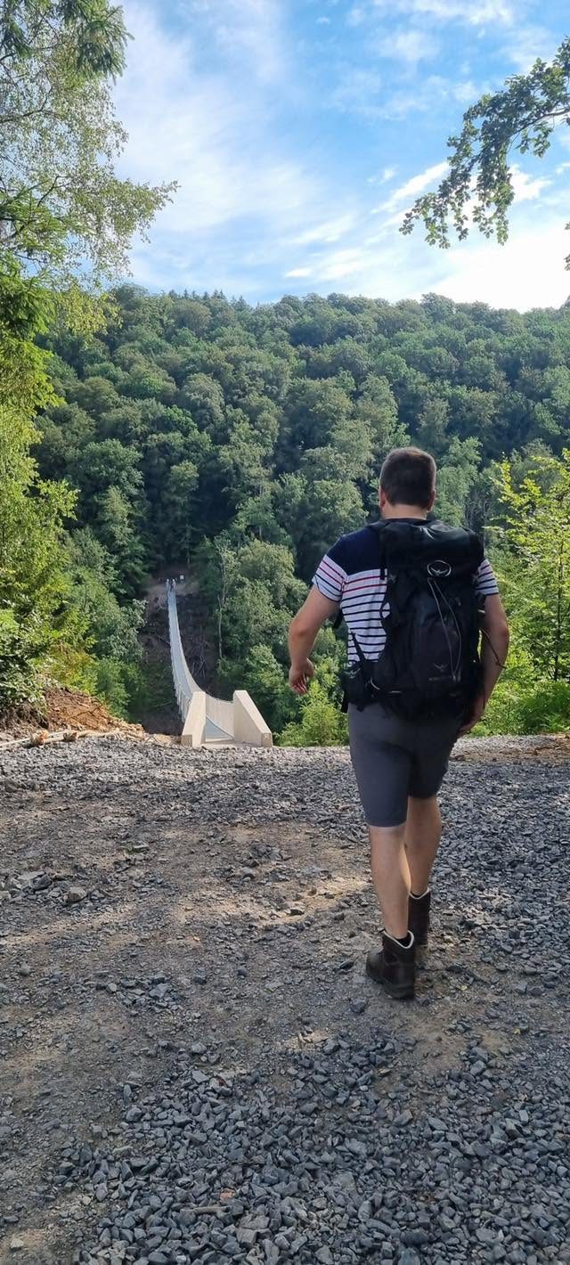 Le guide de Guide Rando Trail, sac au dos, marche vers l'entrée de la passerelle