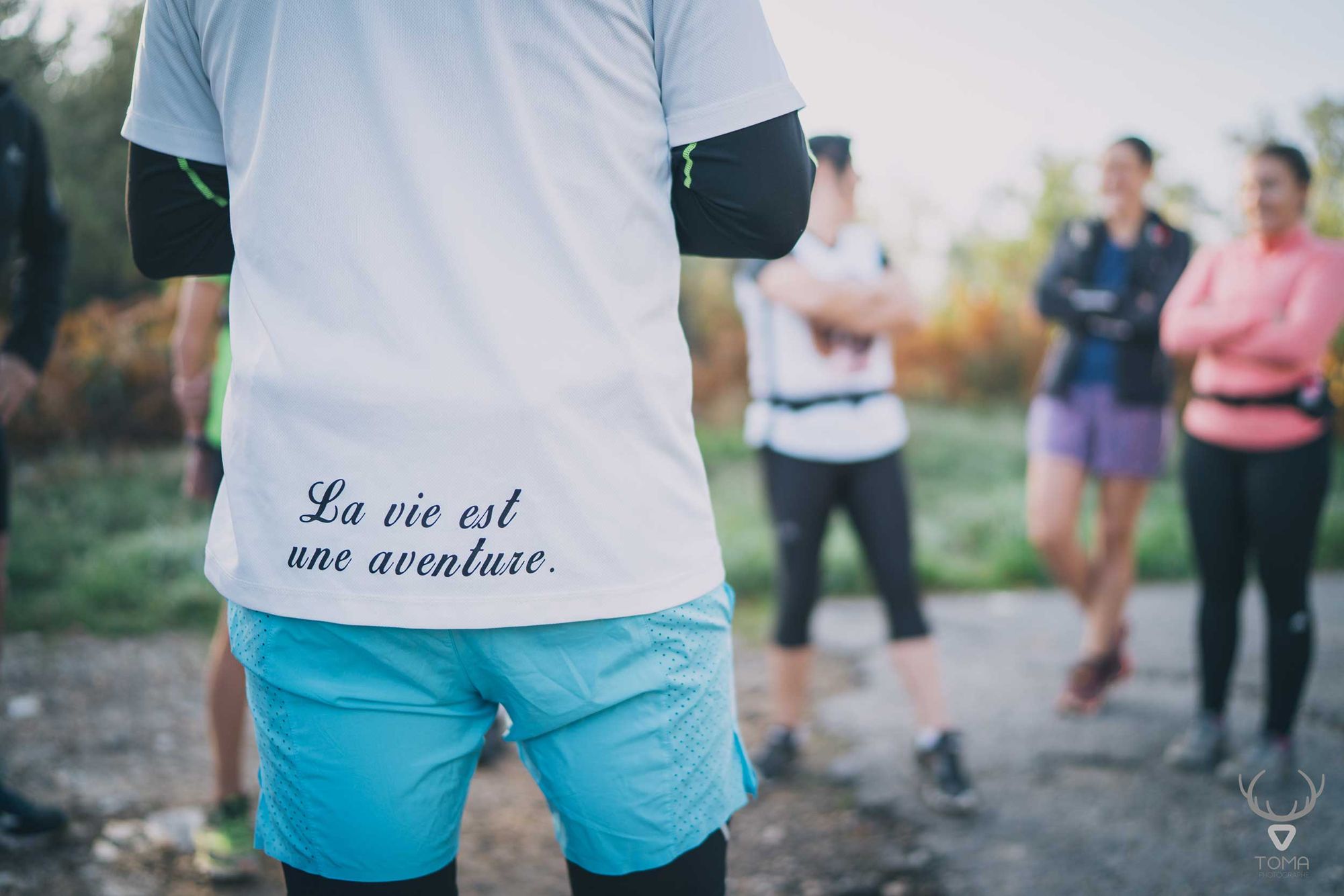 Dos d'un guide dont le t-shirt porte « La vie est une aventure »