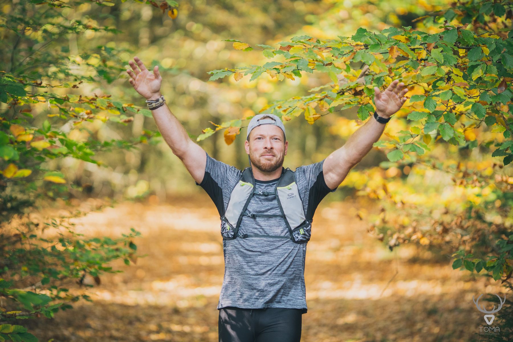 Un traileur les bras levés sur un chemin d'automne